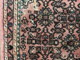 an antique persian rug with a pink background and a blue border