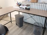 a desk with a chair and a trash can in the corner