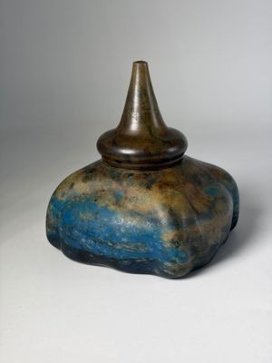 a blue and brown vase sitting on a white surface