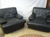 une paire de fauteuils inclinables en cuir noir dans une pièce où se trouve un tapis au sol