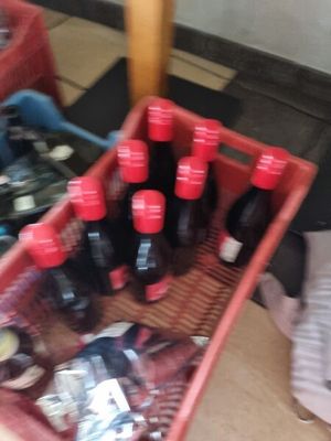 many bottles of soda in a red basket on the floor
