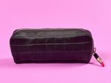 une trousse en cuir noir sur fond rose