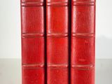 three red books sitting on top of each other on a white surface