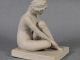 statue of a woman sitting on a block with her hands on her knees