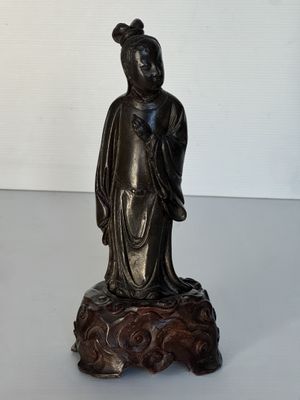 une statue représentant une femme assise sur un rocher
