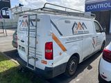 a white van parked in a parking lot with a ladder on the back of it