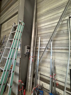 many ladders that are leaning against a wall in a warehouse