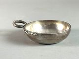 an old silver bowl with a handle on a white surface