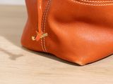 an orange leather purse with a zipper on top of a wooden table