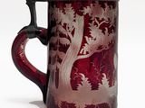 une tasse en verre rouge avec un couvercle noir et l'image d'un cerf