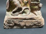 a statue of a man sitting on a rock with a snake