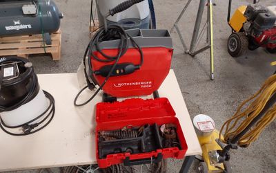 une boîte à outils rouge posée sur une table, à côté d'autres outils