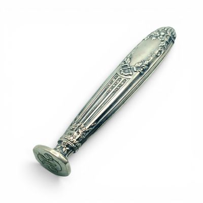 une cuillère en argent avec un manche sur une surface blanche