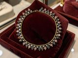 deux coffrets en velours rouge sur lesquels est posé un collier en or et diamants