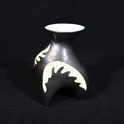 un petit vase noir orné d'un motif blanc