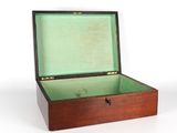 une petite boîte en bois avec un couvercle vert posée sur une surface blanche