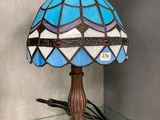 lamp on a glass shelf in a room with a wall behind it