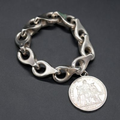 a close up of a silver bracelet with a coin on it