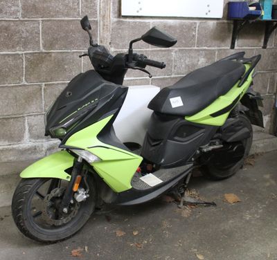 a green and black scooter parked in front of a brick wall