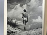 an old black and white photo of a naked man standing on a beach