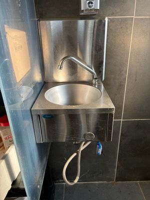 a stainless steel sink in the corner of a bathroom