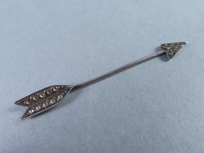 une image représentant une broche en forme de flèche argentée sur un fond bleu