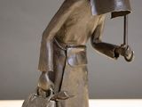 a statue of a man holding an umbrella and a bag