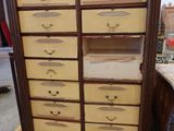 une grande armoire en bois comportant de nombreux tiroirs et surmontée de tiroirs