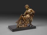 une statue en bronze représentant une femme assise sur une chaise