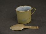 a yellow cup with a spoon on a table