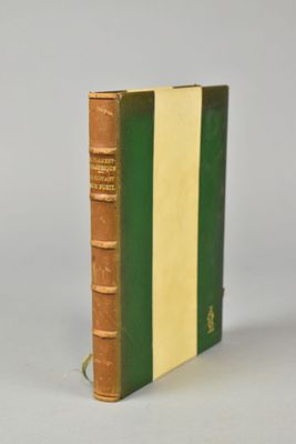 un vieux livre posé sur une table blanche, à côté d'un livre vert et jaune