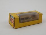 une petite voiture miniature dans une boîte jaune posée sur une surface blanche