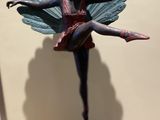 statue of a ballerina with a peacock tail on a wooden table
