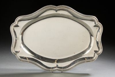 silver plate with scalloped edge on stand against black background