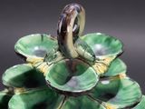 a green vase with a bird sitting on top of it