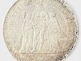 une image représentant une pièce d'argent sur laquelle figurent une femme et deux hommes