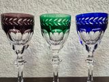 four wine glasses are lined up on a table with a wall in the background