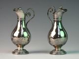 two silver vases sitting next to each other on a table