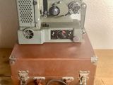 un vieux projecteur de cinéma posé sur une valise