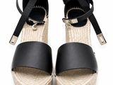 espadrilles en cuir noir ornées de boucles métalliques sur fond blanc