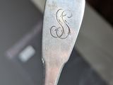 someone is holding a spoon with the letter s on it