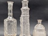 three clear glass bottles sitting next to each other on a table