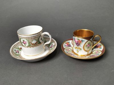 two cups and saucers with gold rims on a table