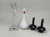 three vases, a glass vase, and a candle holder on a table