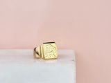 une bague en or sur laquelle figure la lettre « r »