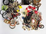 a lot of jewelry on a table with scissors and a picture frame