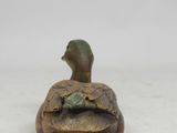 a small statue of a duck sitting on top of a turtle shell