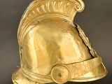 an antique gold helmet on a clear stand against a black background