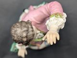 a figurine of a man in a pink shirt and green pants