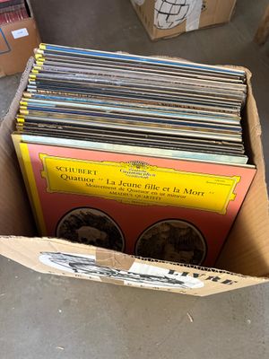 une boîte remplie de disques posée par terre, à côté d'autres boîtes